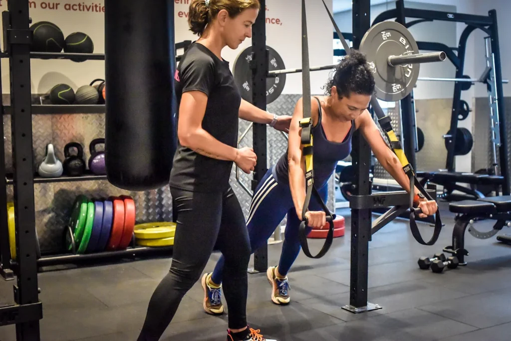 Personal trainer guiding a client's form doing exercises