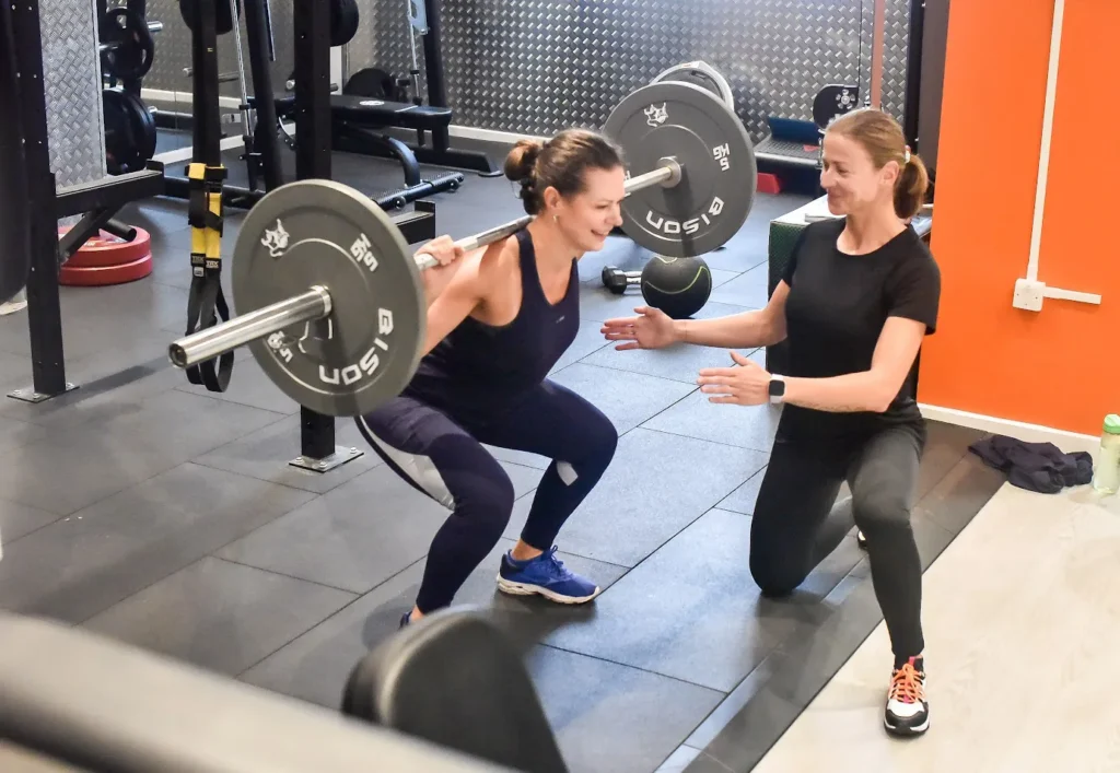 Personal trainer guiding a woman weight lifting